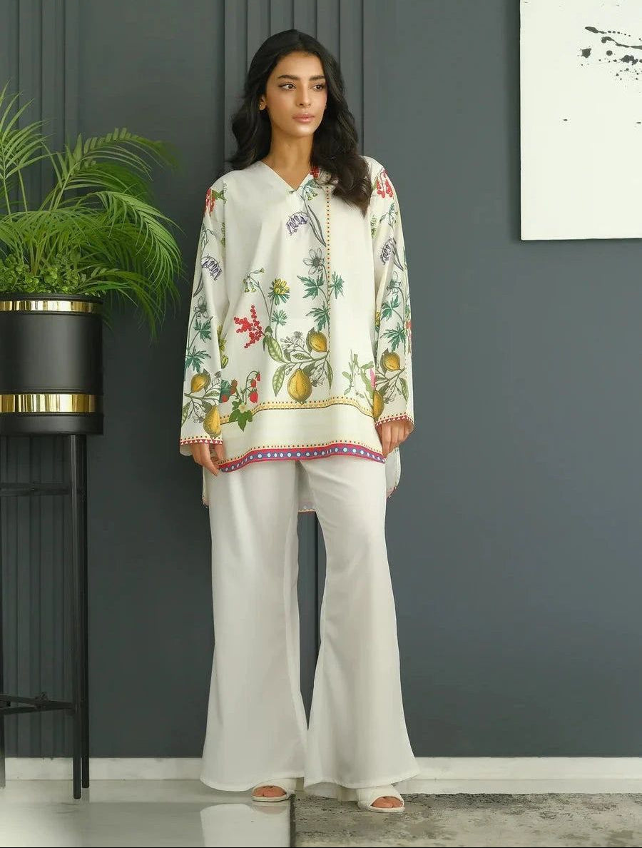 Woman wearing a floral blouse and white pants in a room with a plant and wall art. MARTIVA