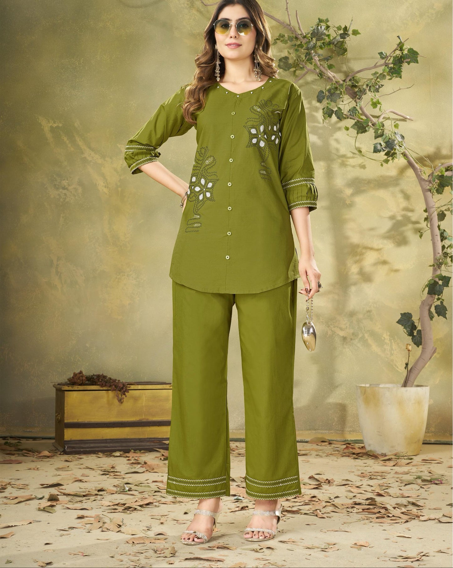 Woman wearing a green outfit with floral embroidery in a decorative setting.