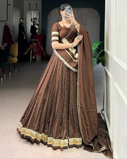Woman in a brown saree with gold details taking a mirror selfie.