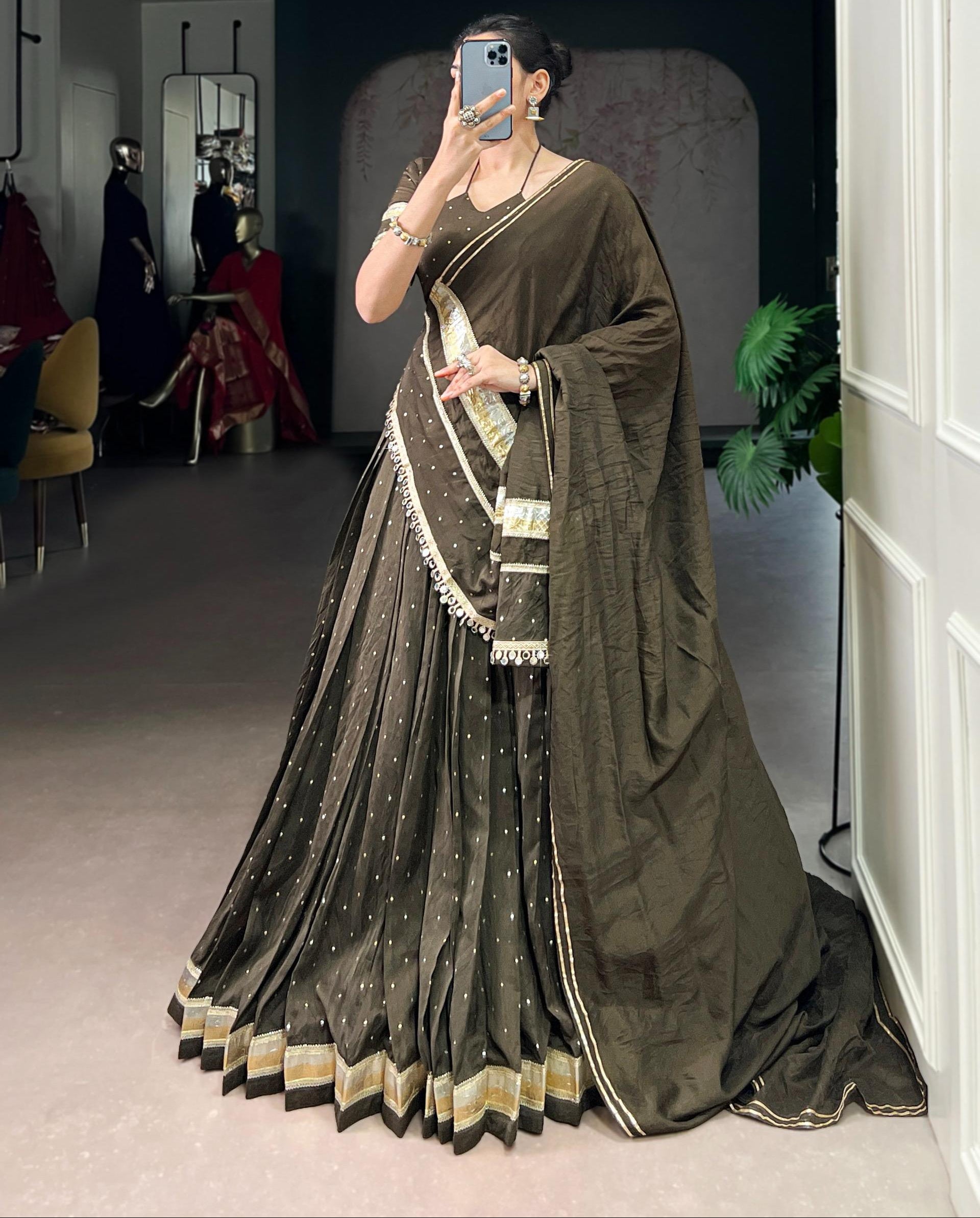 Person wearing a dark green saree with gold border in an indoor setting.