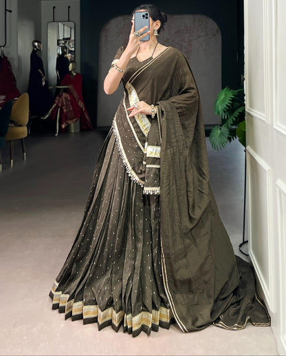 Person wearing a dark green saree with gold border in an indoor setting.