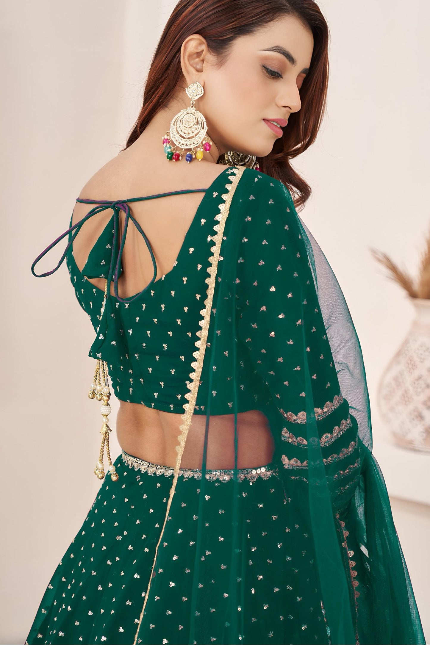 Woman wearing a green traditional outfit with intricate designs and jewelry.
