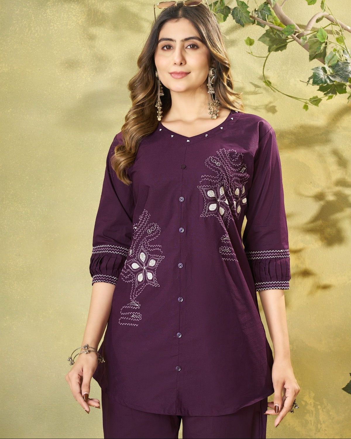 Woman wearing a purple embroidered outfit on a green leafy background