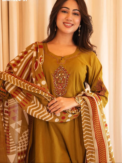 Woman wearing a traditional outfit with a patterned dupatta against a beige curtain background