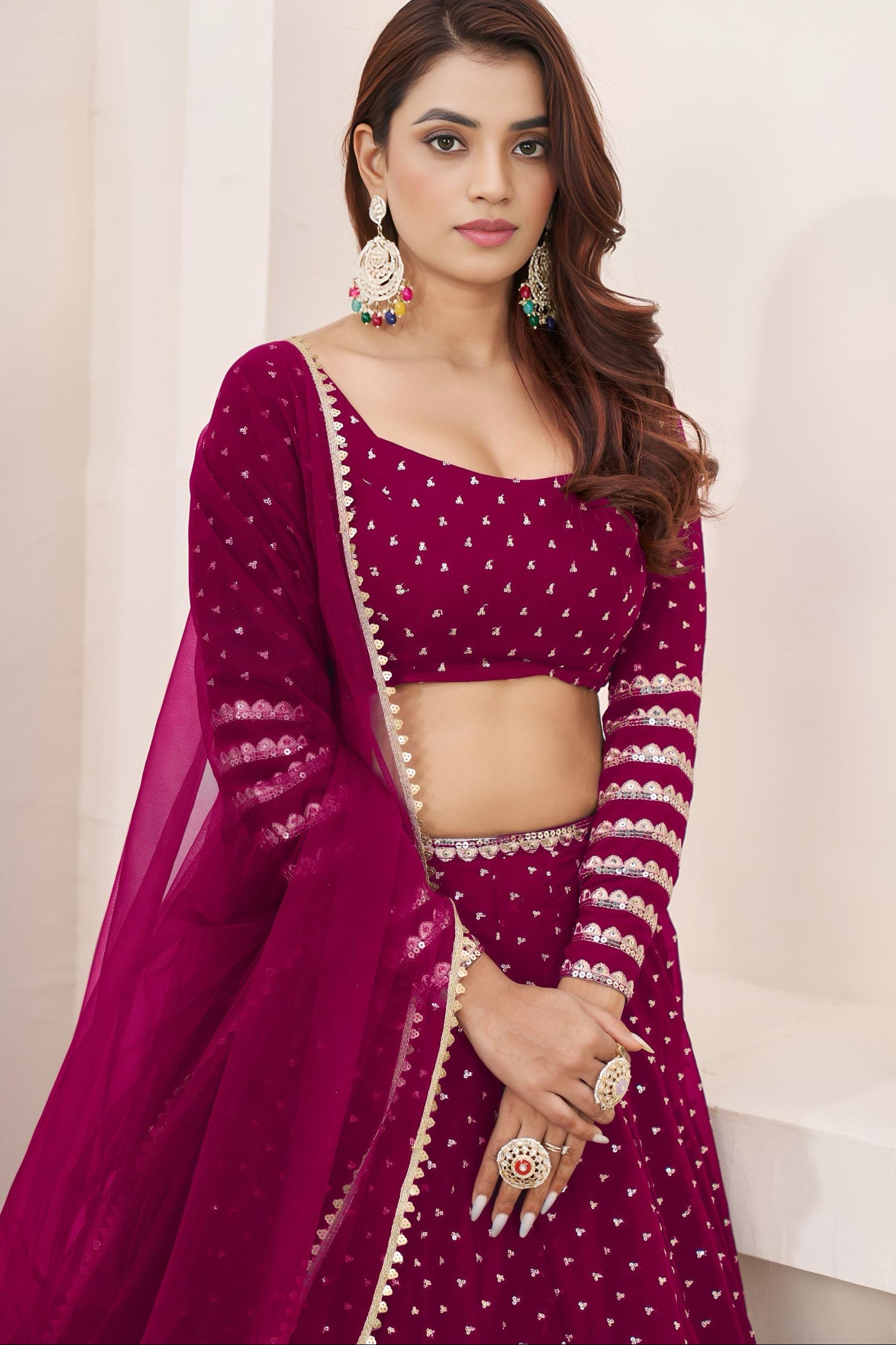 Woman wearing a magenta traditional outfit with a plain background