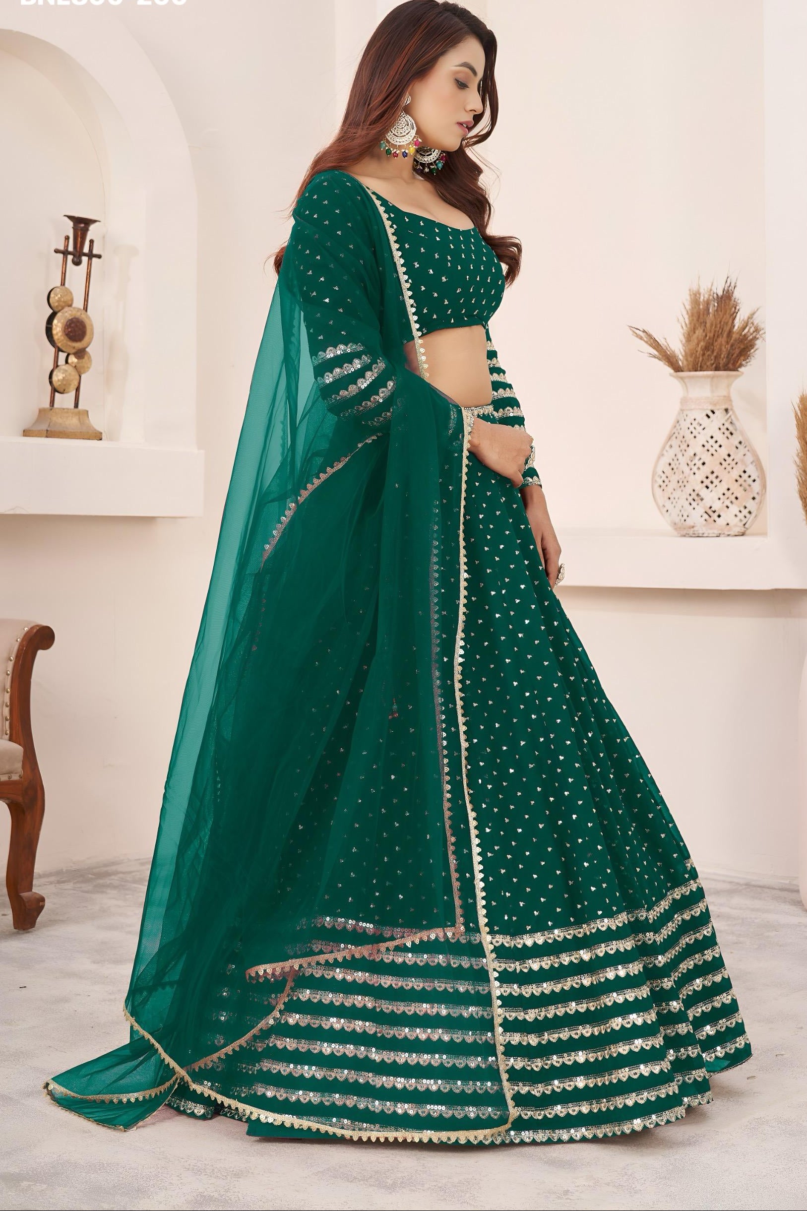 Woman wearing a green embroidered lehenga in an indoor setting