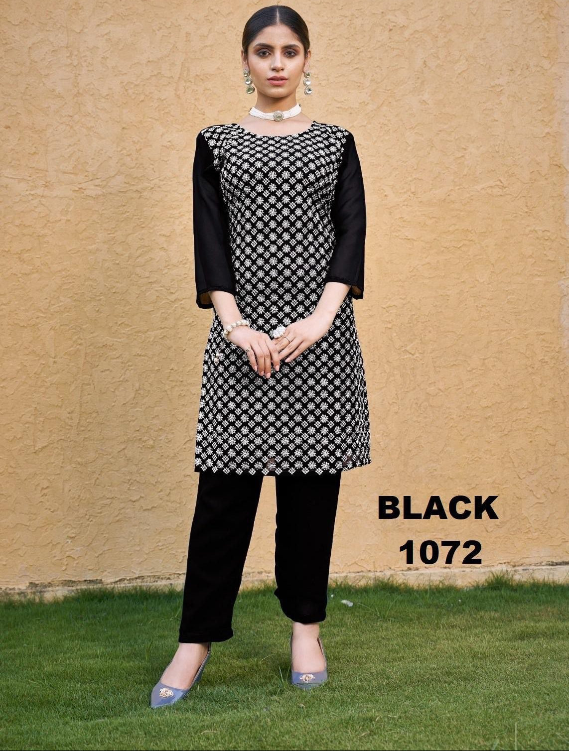 Woman wearing a black and white patterned kurta with black pants against a beige wall.