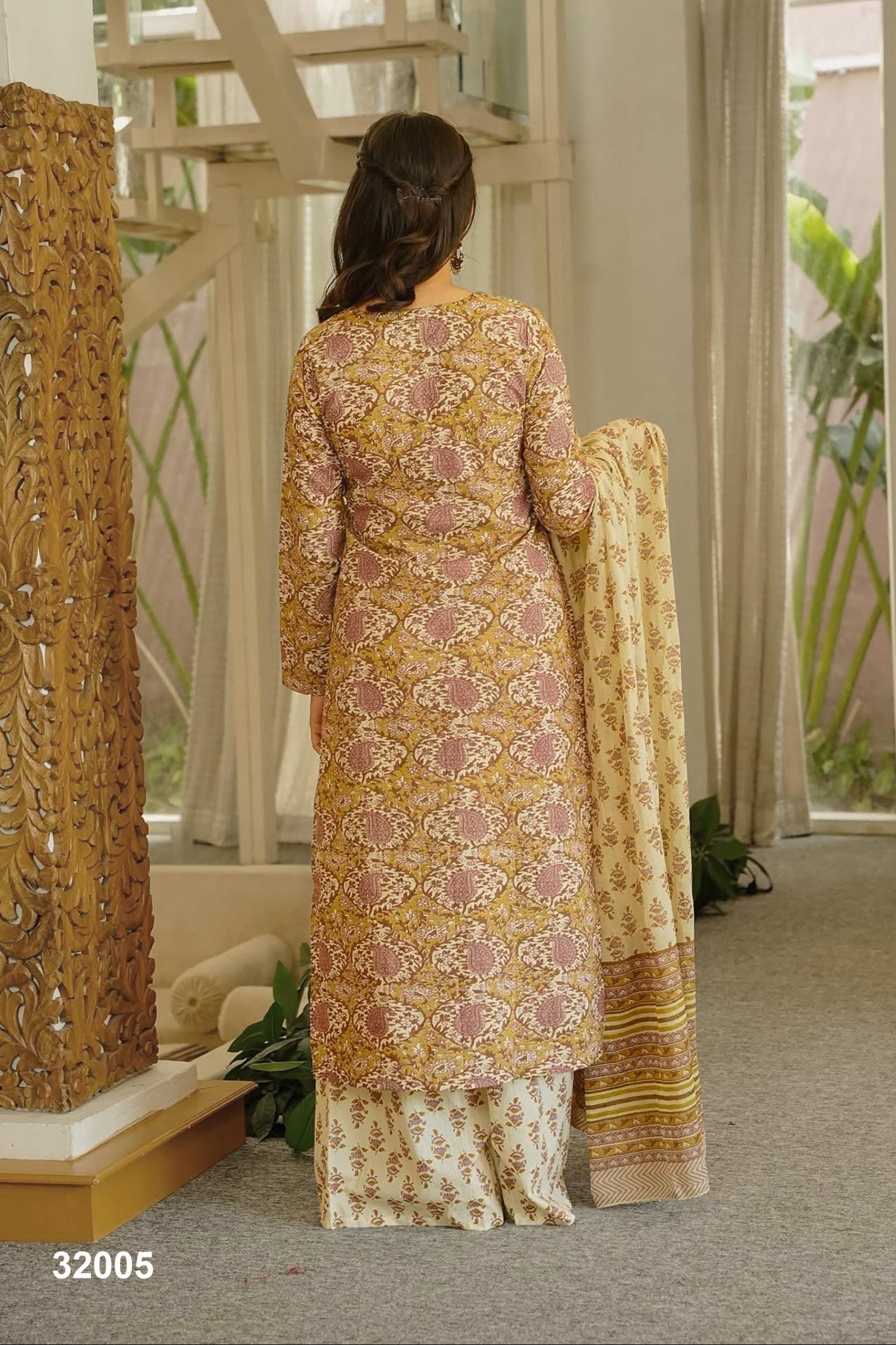 Woman in a patterned outfit standing in a room with decorative elements.