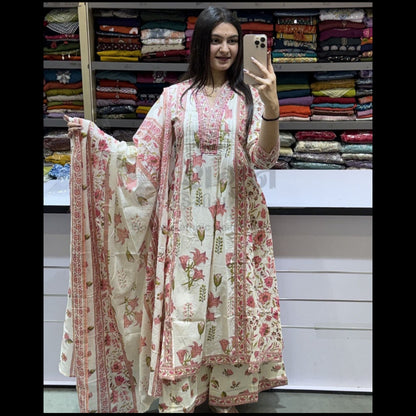 Woman holding a floral dress in front of a fabric store display.