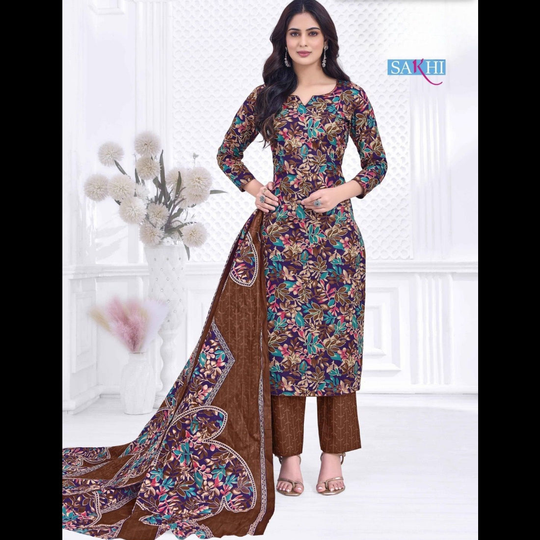 Woman wearing a floral printed suit with a brown dupatta on a white background