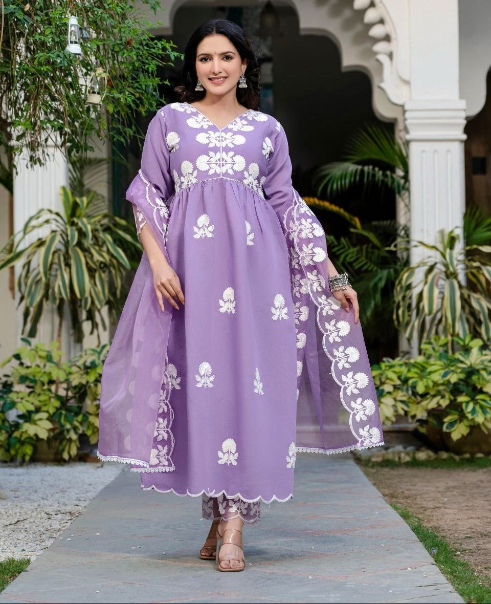 Woman in a purple dress with white floral patterns standing outdoors.