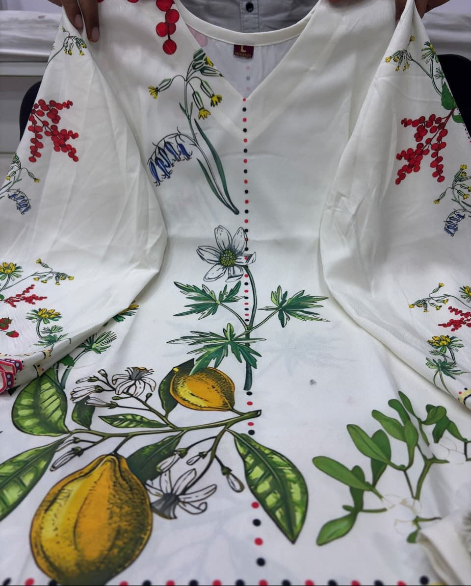 White dress with colorful floral and fruit patterns held by a person. MARTIVA)