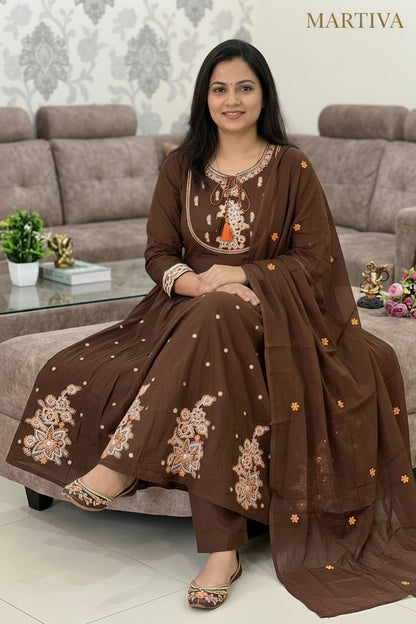 Woman sitting on a sofa wearing a brown embroidered outfit with size options displayed.