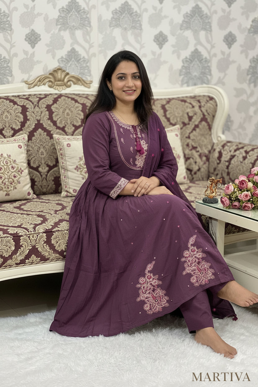 Woman in a purple embroidered outfit sitting on a patterned sofa with size options displayed.
