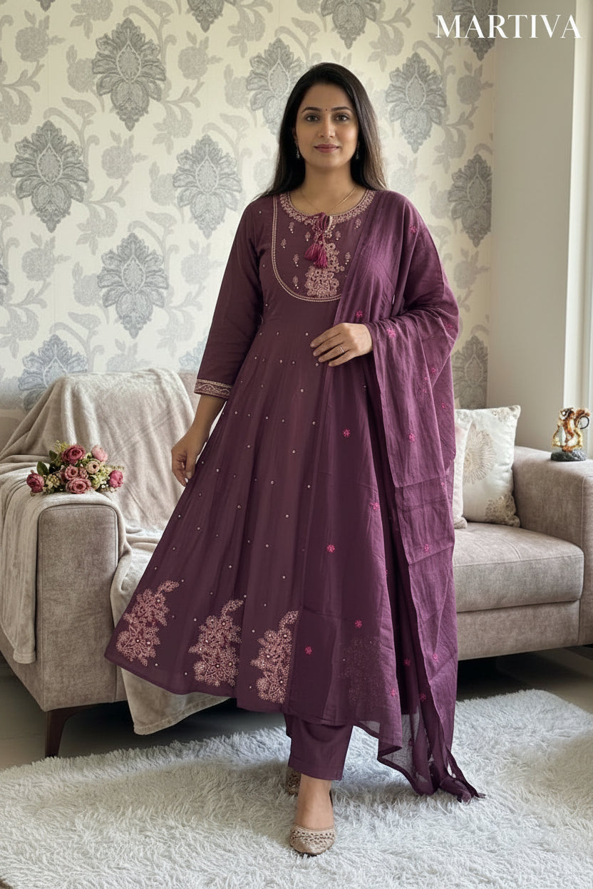 Woman wearing a purple embroidered outfit standing in a living room.