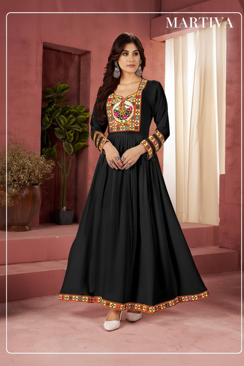 Woman wearing a black traditional outfit with colorful embroidery in a pink room.