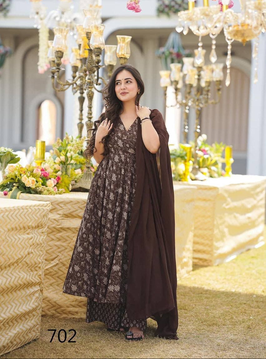 Woman in a floral dress standing in an elegant indoor setting with chandeliers and floral arrangements.