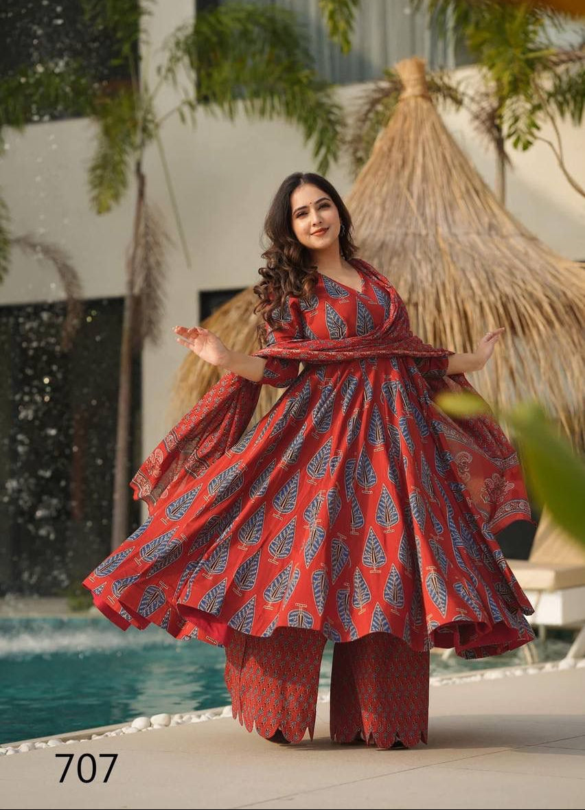 Woman in a red and blue patterned outfit standing by a poolside with greenery in the background.