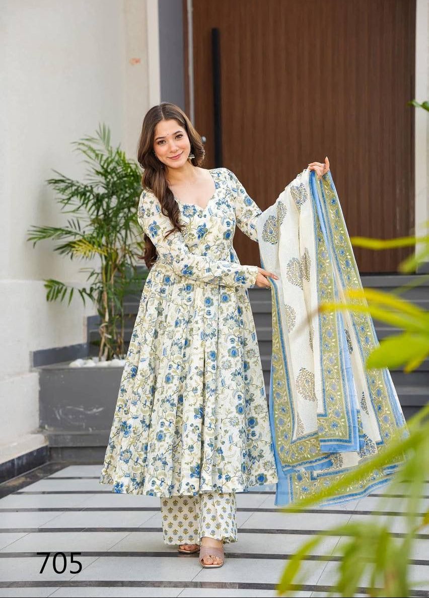 Woman in a floral dress holding a matching dupatta on a staircase with plants in the background