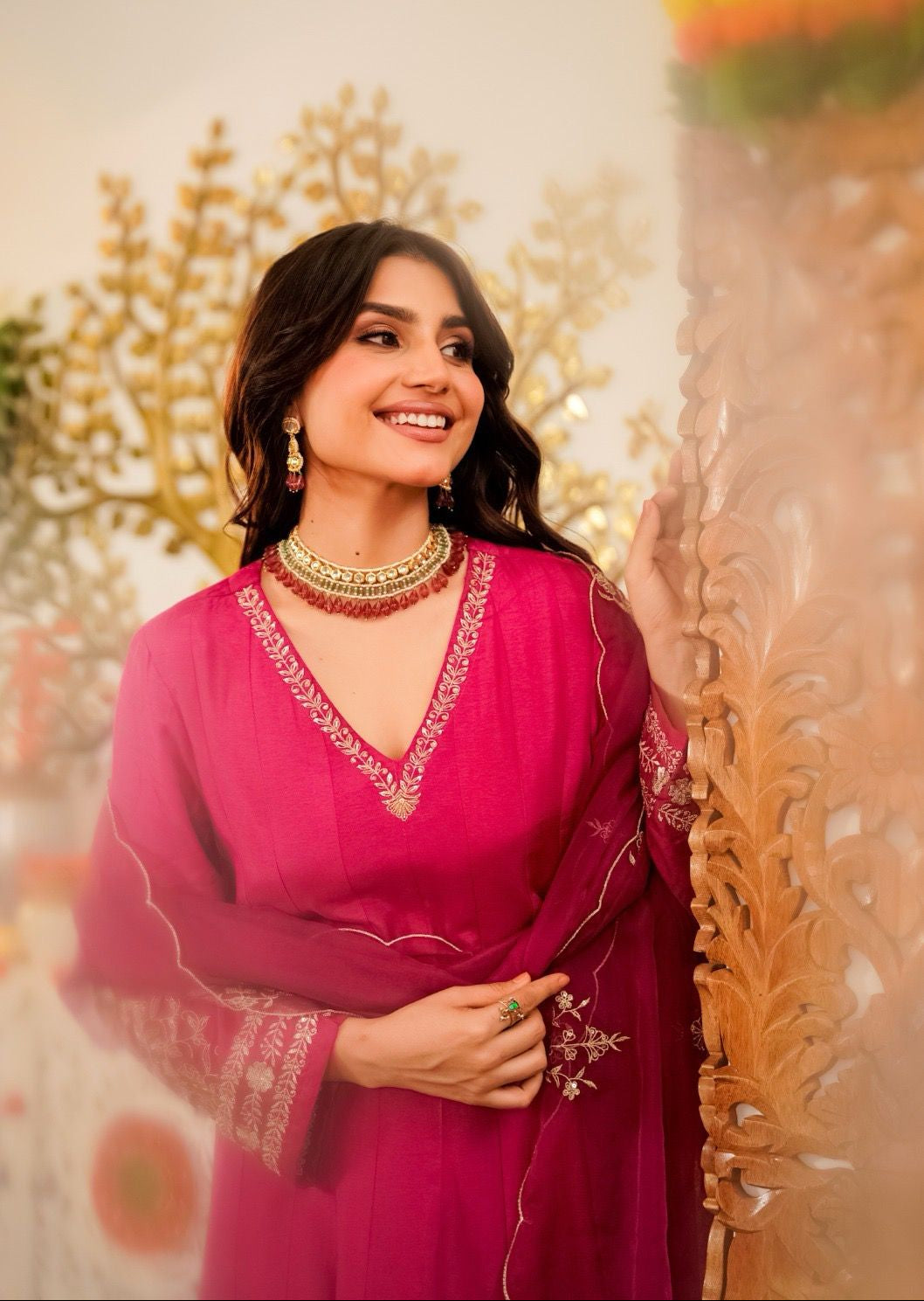 Woman in a pink traditional outfit with floral decorations in the background