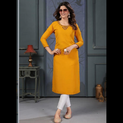 Woman wearing a mustard yellow kurta with intricate detailing, posing indoors.