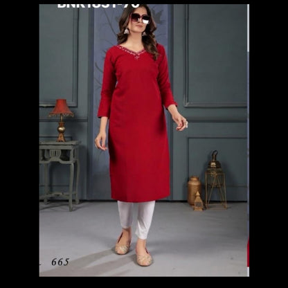 Woman wearing a red kurta with white pants in a room setting