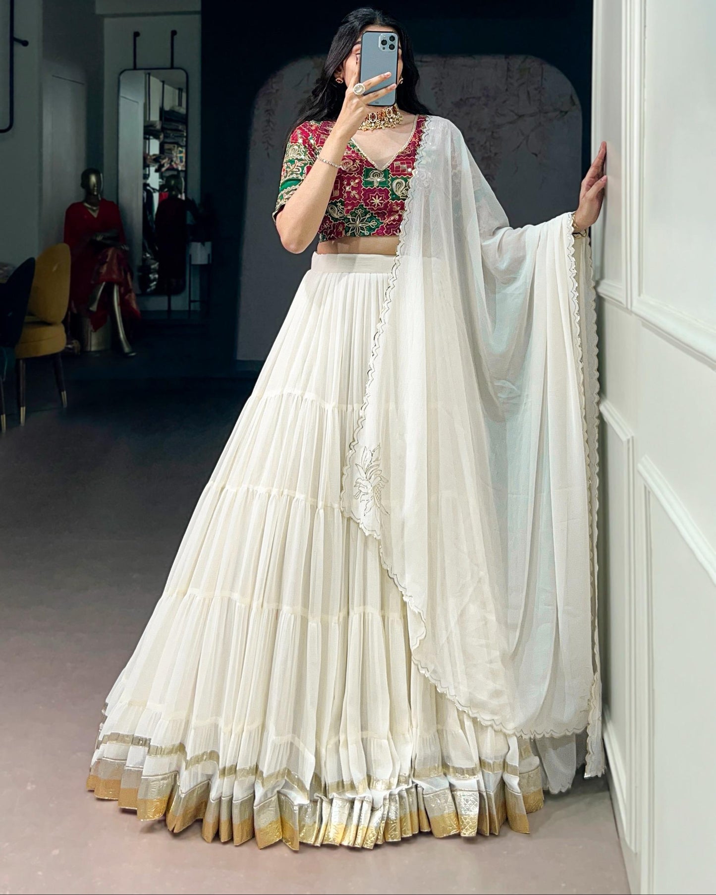 Woman in a white saree with a colorful blouse taking a mirror selfie.