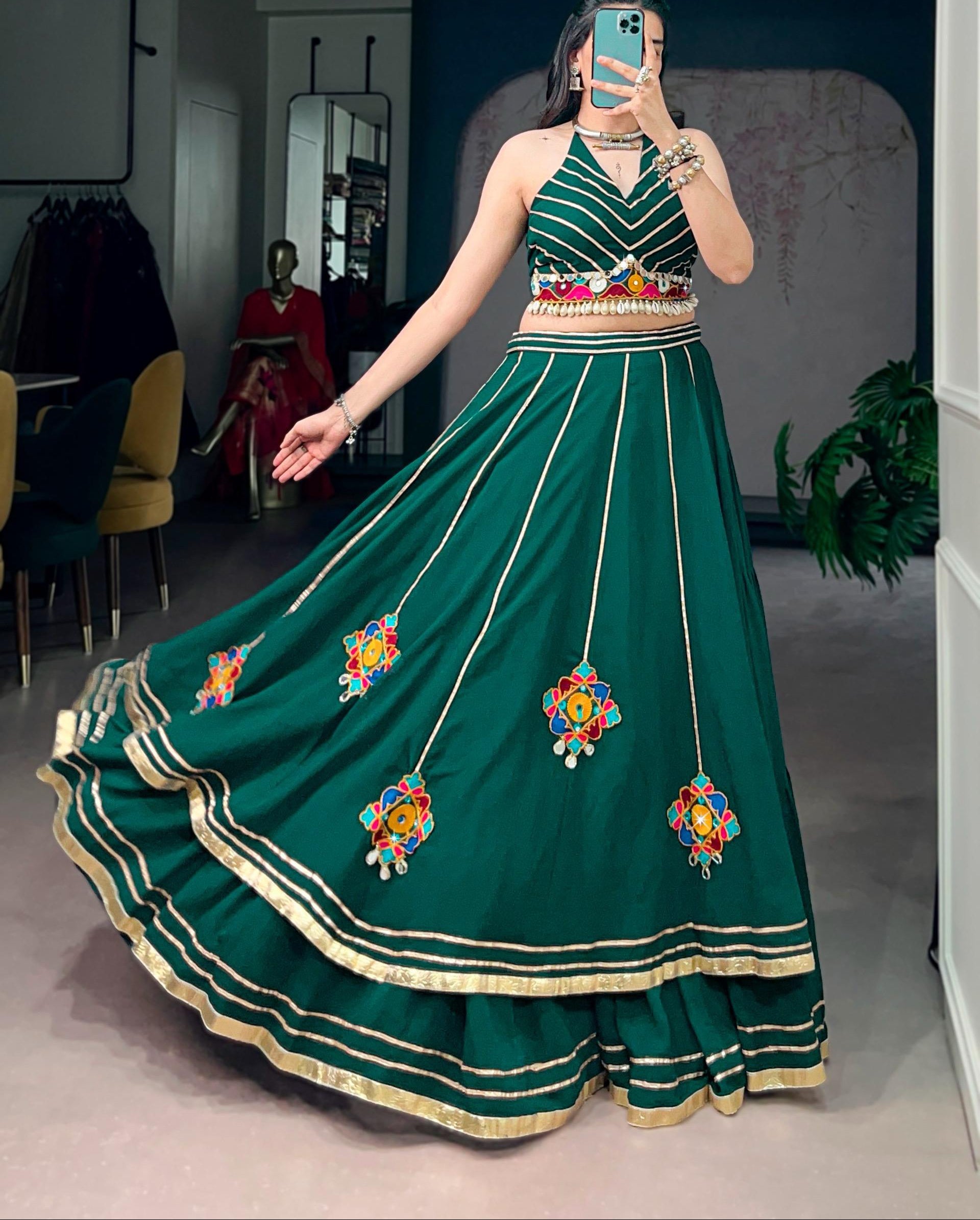 Woman wearing a green embroidered traditional outfit in a room.
