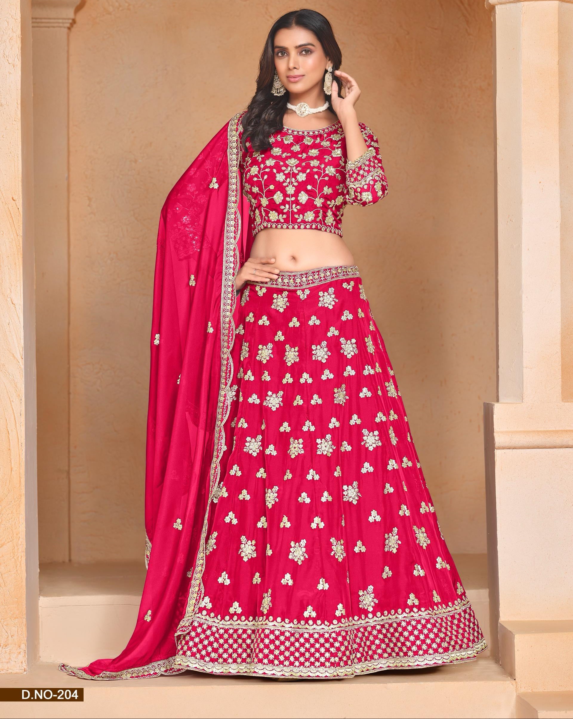 Woman in a pink embroidered traditional outfit standing in a decorative setting.