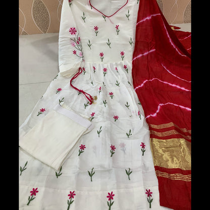 White embroidered outfit with pink flowers and a red saree with gold border on a neutral background