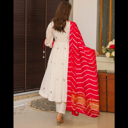 Woman wearing a white kurta with a red and white dupatta in an indoor setting.