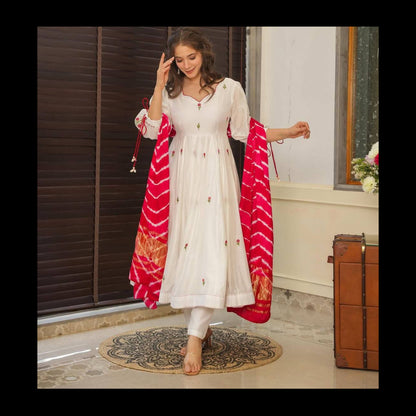 Woman in a white traditional outfit with a red and pink dupatta in a room.
