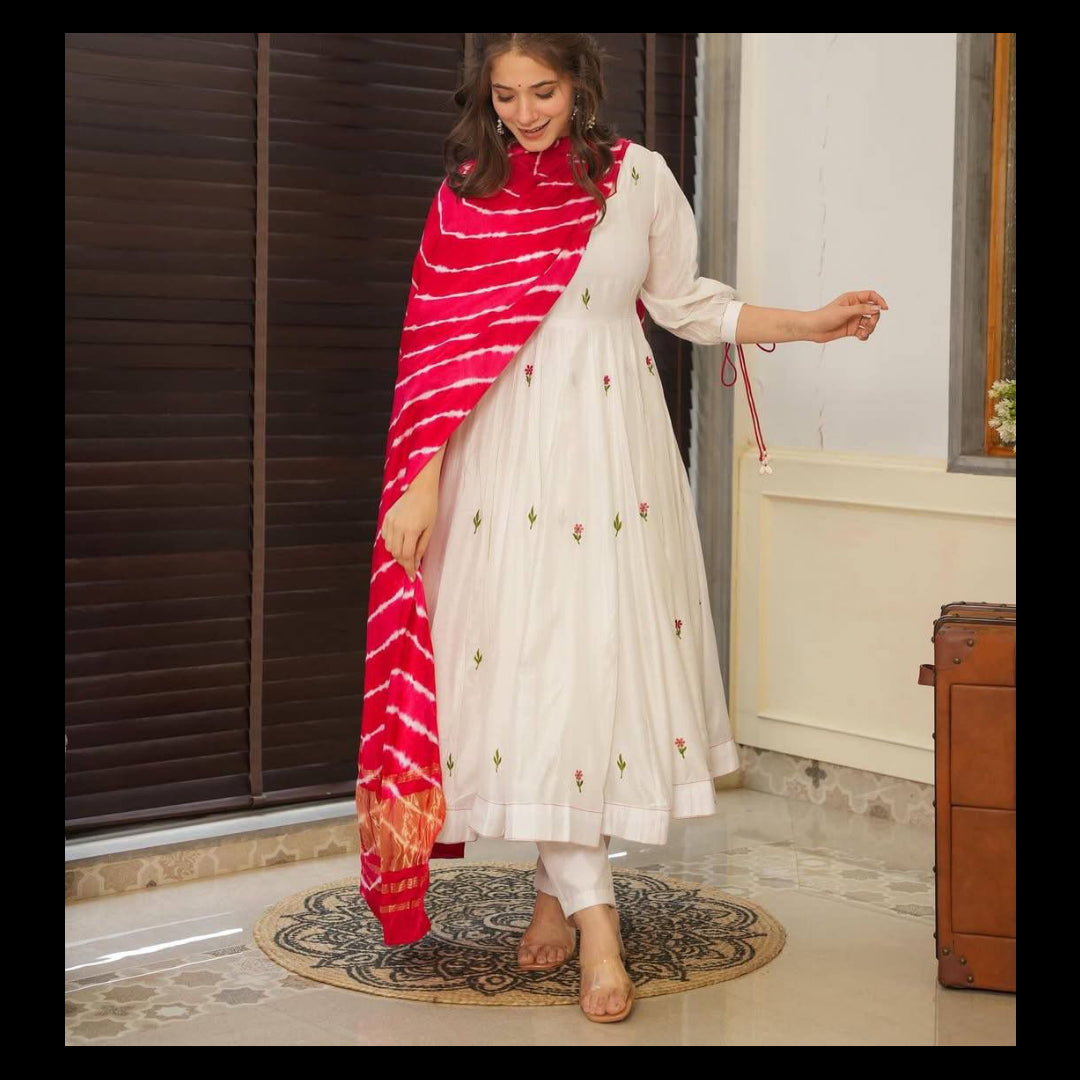 Woman wearing a white outfit with a red and pink dupatta indoors.