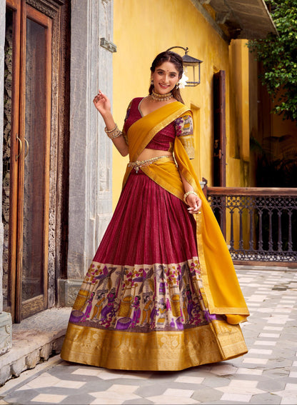 Woman in a traditional maroon and yellow saree standing in front of a yellow building.