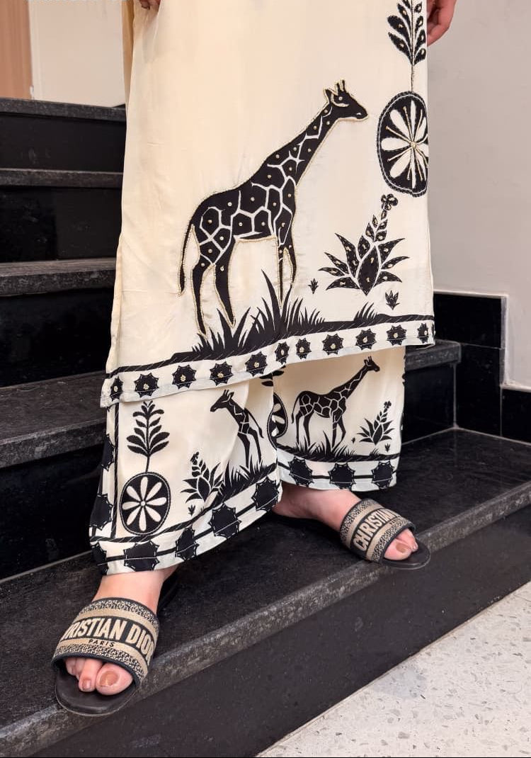 Person wearing a white outfit with black giraffe and floral patterns, standing on stairs.