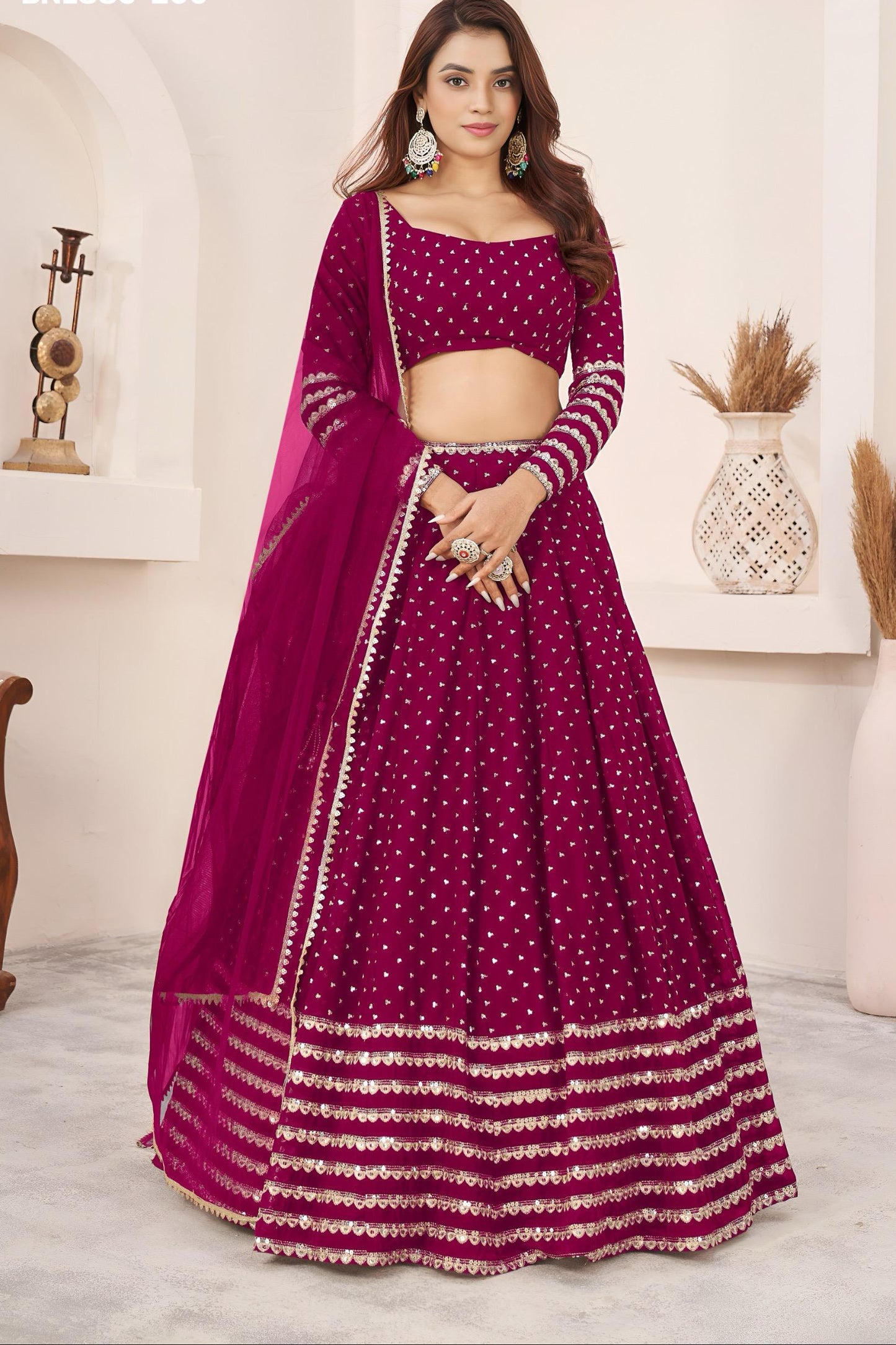 Woman wearing a vibrant purple traditional outfit with intricate designs indoors.