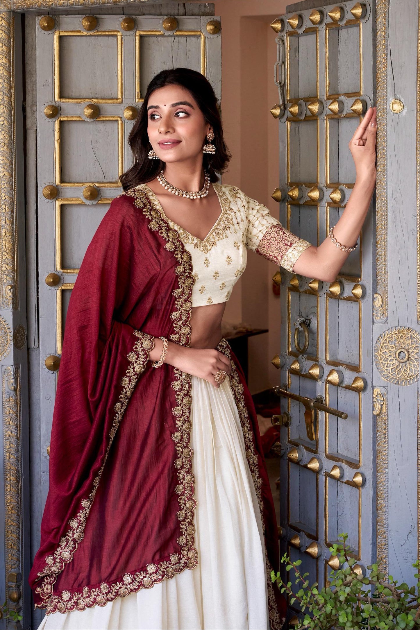 Woman in traditional attire standing in front of a decorative door.