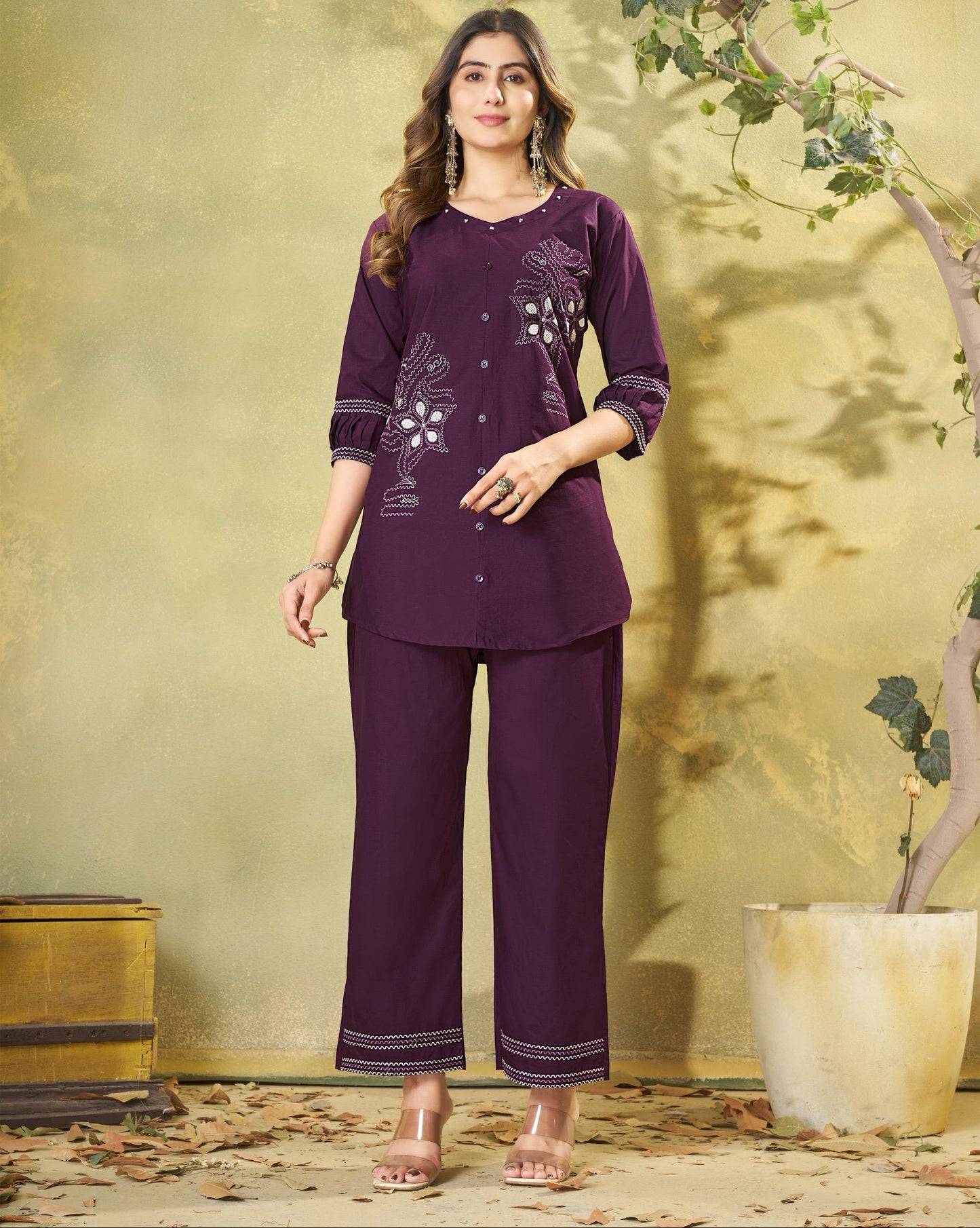 Woman wearing a purple outfit with floral patterns in a decorative setting.