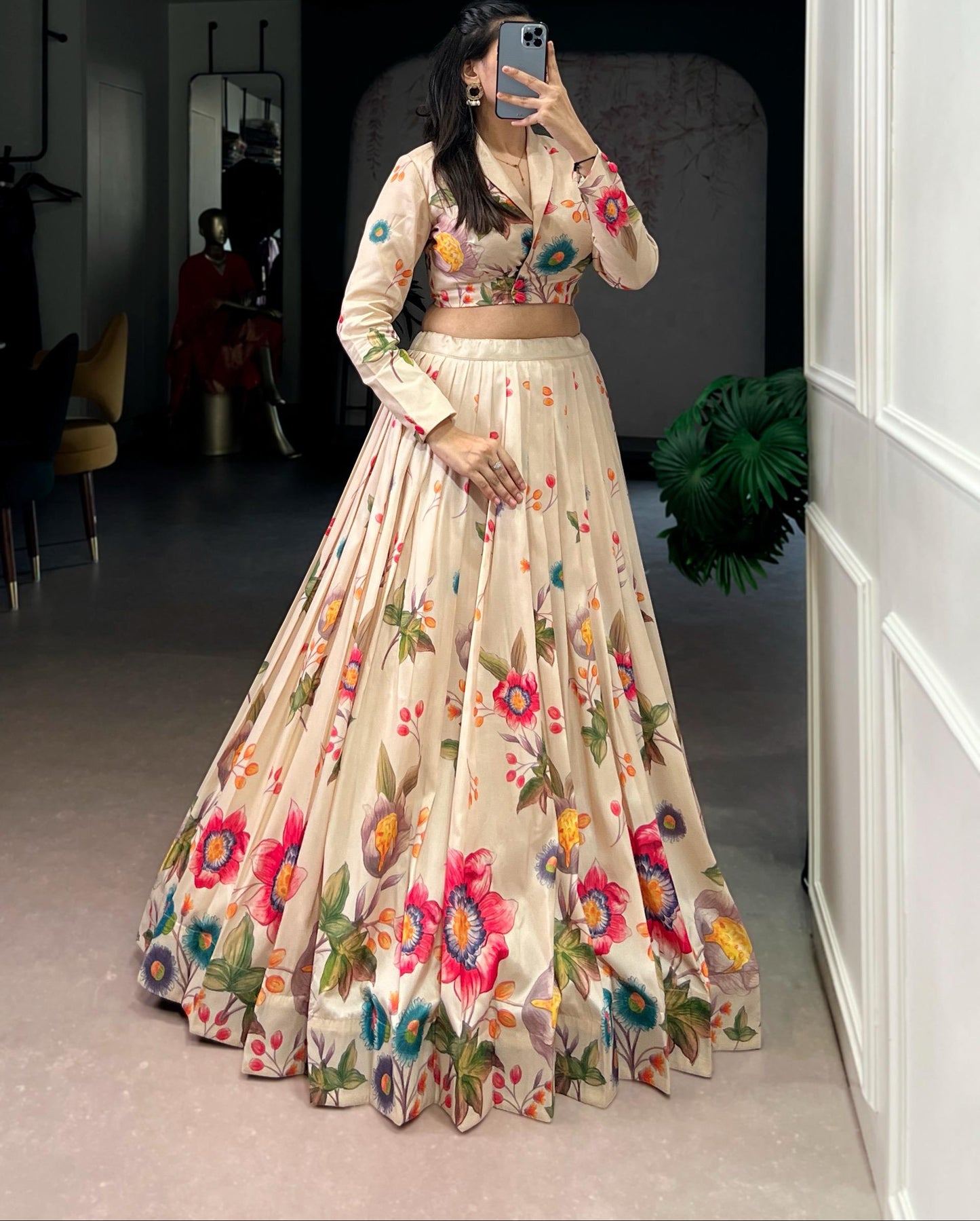 Woman wearing a floral dress taking a mirror selfie in a room.