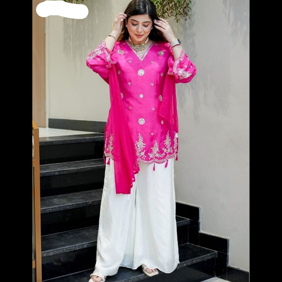 Woman wearing a bright pink top with white pants on a staircase.