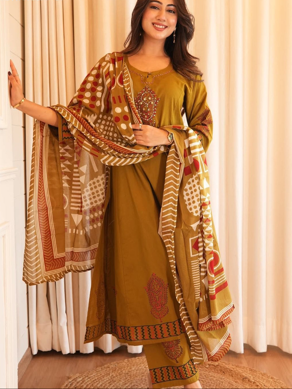 Woman wearing a traditional outfit with a patterned dupatta against a neutral background